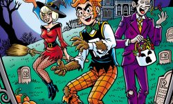 Archie and Jughead, wearing Halloween costumes, stand in a cemetery in front of Eyegore Estates, a creepy rundown haunted house, at night. Carved jack-o-lanterns are on the ground and Jughead is snacking on candy from his trick or treat bucket. Sabrina floats behind them on a broom, and an image of the Wicked Trinity -- Amber, Sapphire, and Jade -- floats behind them against the backdrop of a full moon. Amber is holding flames in an open palm. Bats fly above them.