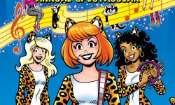 Cover of JOSIE AND THE PUSSYCATS ANNUAL SPECTACULAR. Josie and the Pussycats hold their instruments and look out at the viewer in front of a blue background with a stylized line of sheet music. Sabrina, Alexandra Cabot, and Salem the cat are sitting on and hanging from the sheet music line.